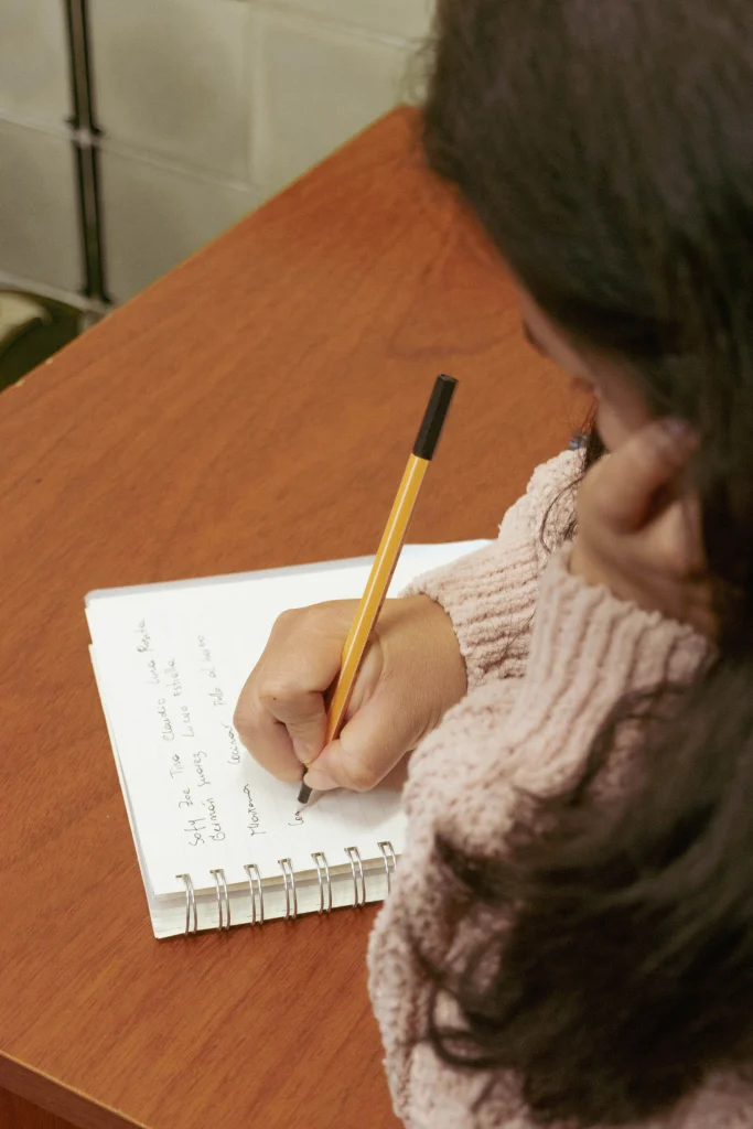 Étudiante prenant des notes sur un carnet papier