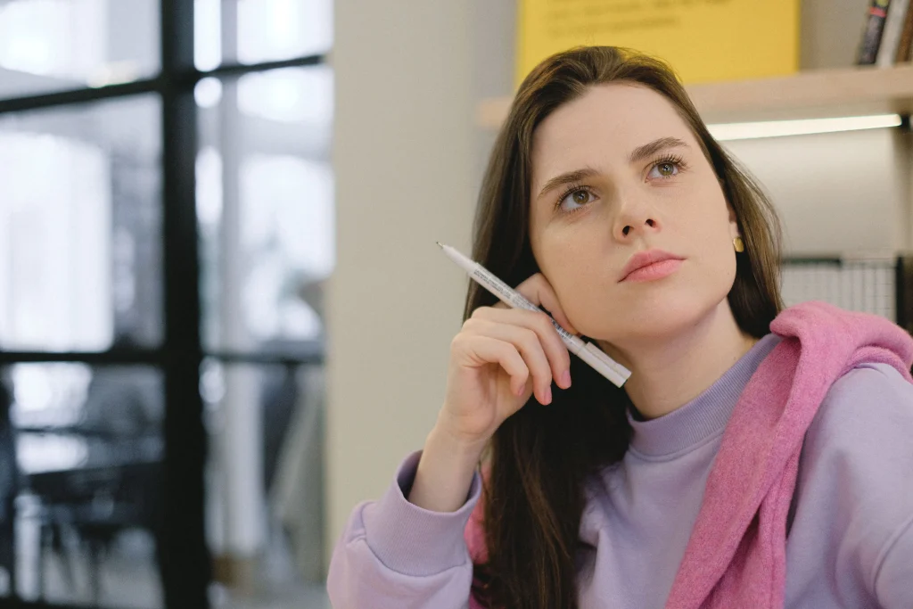 Étudiantes pensive, tenant un stylo à la main