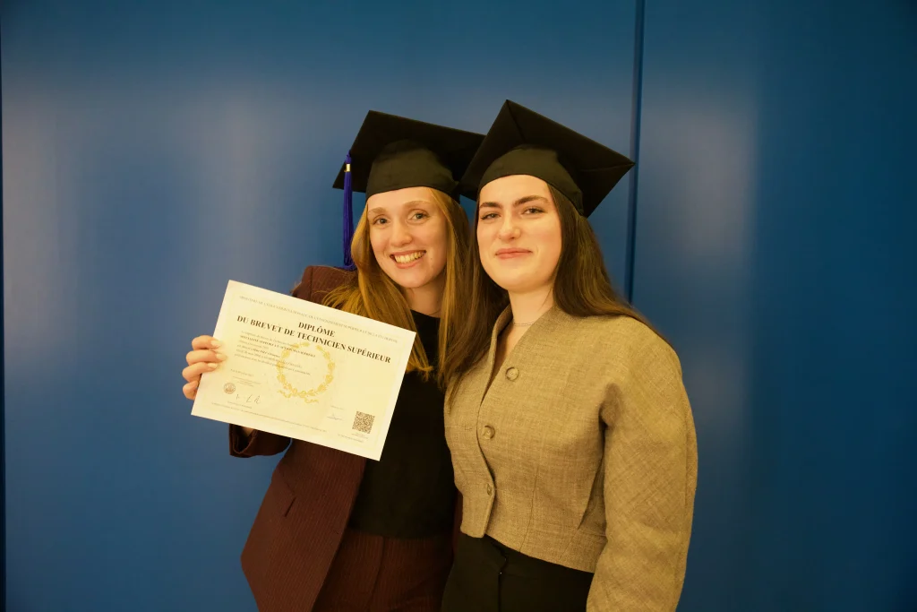 Deux étudiantes diplômées d'un BTS en 2026, portant une toque de cérémonie sur la tête